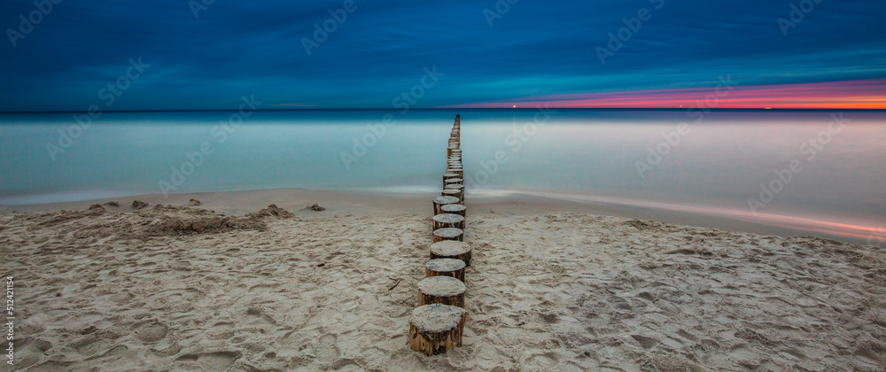 Amazing sunrise over the beach in Chalupy. Seascape with breakwater