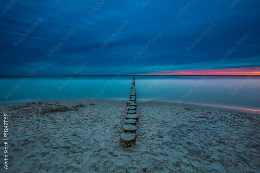 Amazing sunrise over the beach in Chalupy. Seascape with breakwater