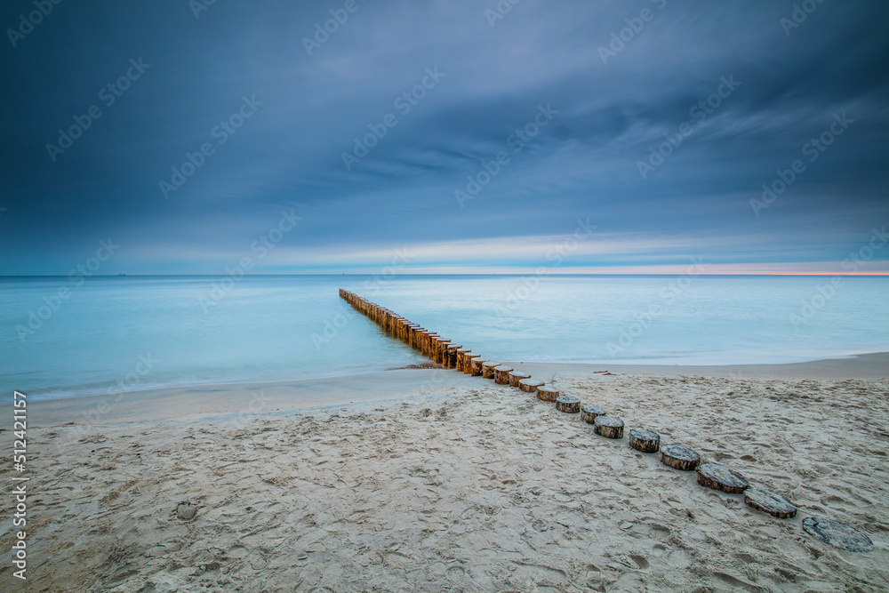 Amazing sunrise over the beach in Chalupy. Seascape with breakwater