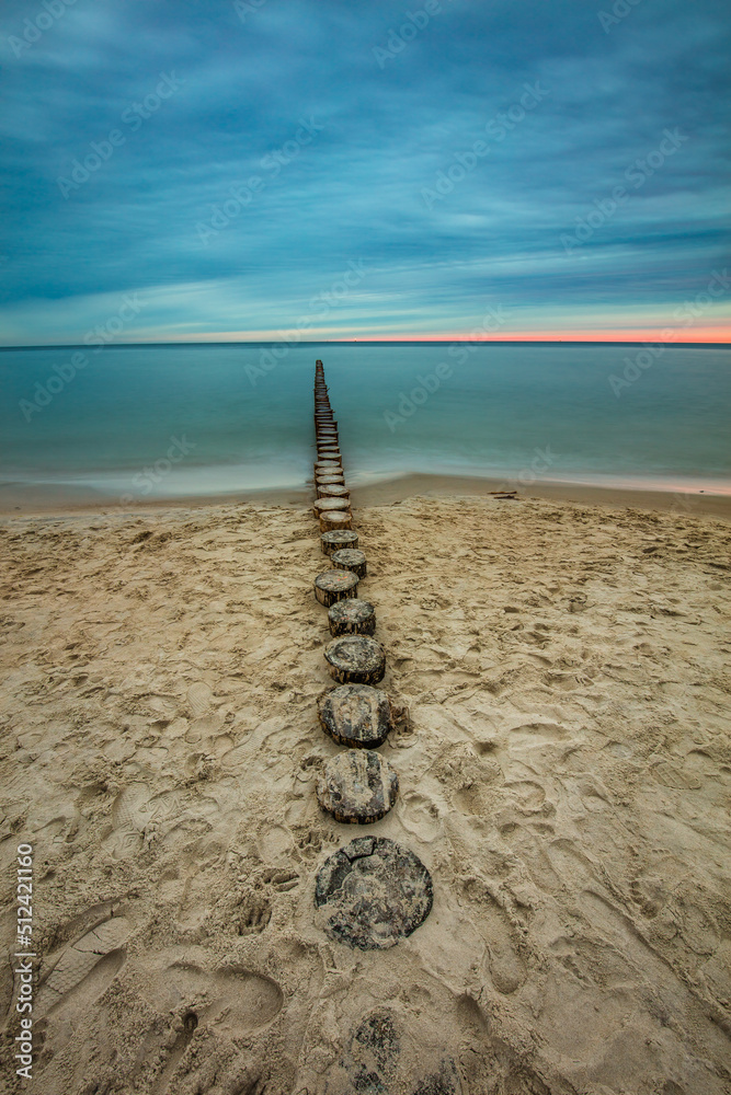 Amazing sunrise over the beach in Chalupy. Seascape with breakwater
