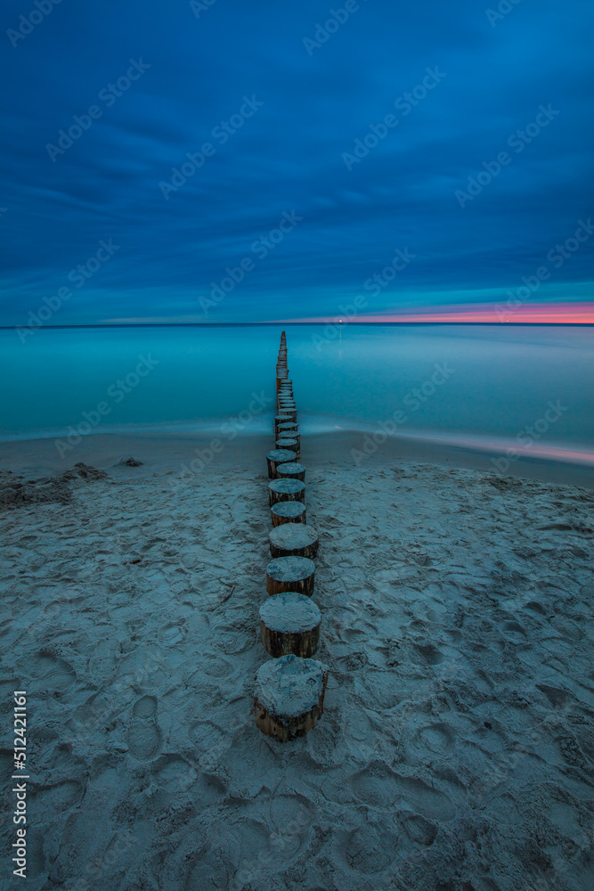 Amazing sunrise over the beach in Chalupy. Seascape with breakwater