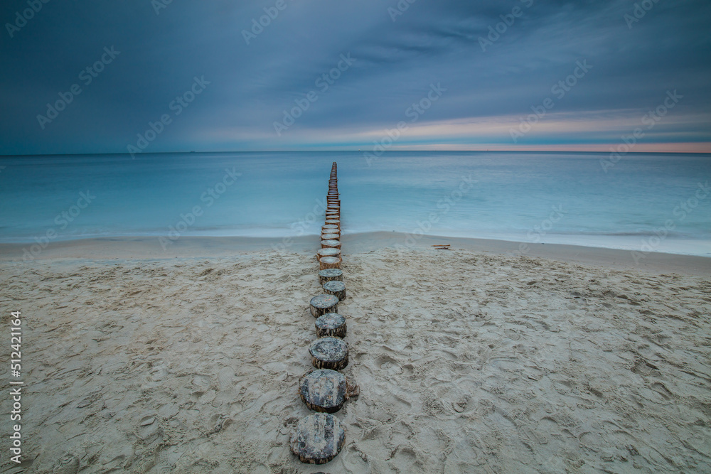 Amazing sunrise over the beach in Chalupy. Seascape with breakwater