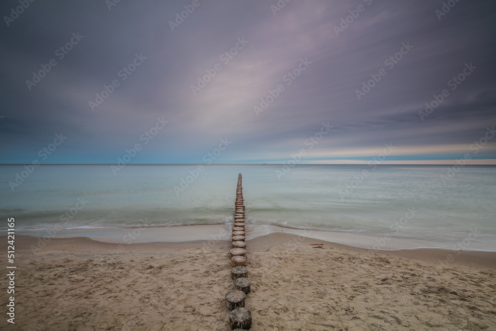 Amazing sunrise over the beach in Chalupy. Seascape with breakwater