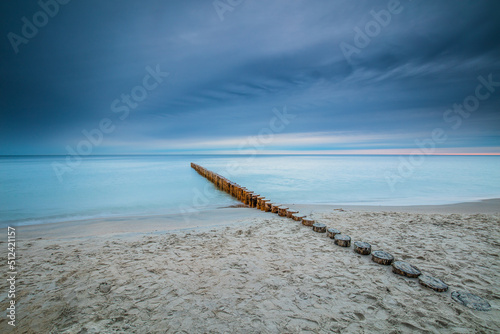 Amazing sunrise over the beach in Chalupy. Seascape with breakwater