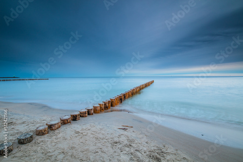 Amazing sunrise over the beach in Chalupy. Seascape with breakwater