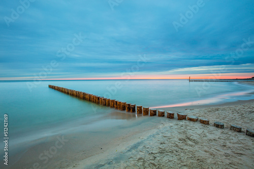 Amazing sunrise over the beach in Chalupy. Seascape with breakwater