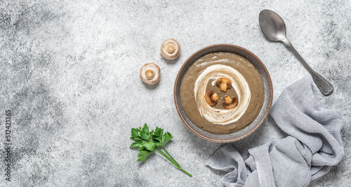 Mushroom cream soup in a bowl on a gray grunge background. Vegetarian organic soup. Healthy food concept. View from above. Banner