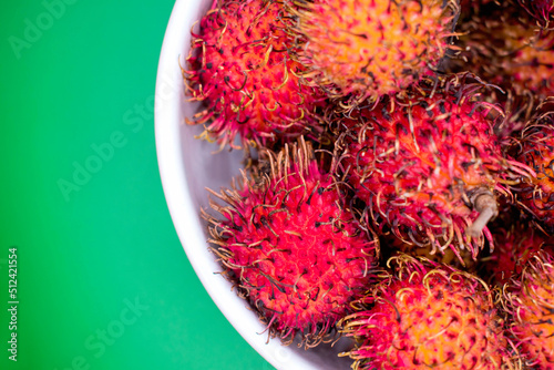 Photography Tazón de fruta Litchi china color roja en un fondo verde en toma cenital a detal
