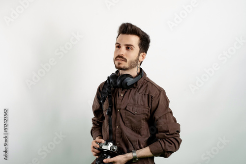 Handsome young man wearing casual clothes posing isolated over white background posing with his dslr camera and his professional photographic equipment. © platinumArt