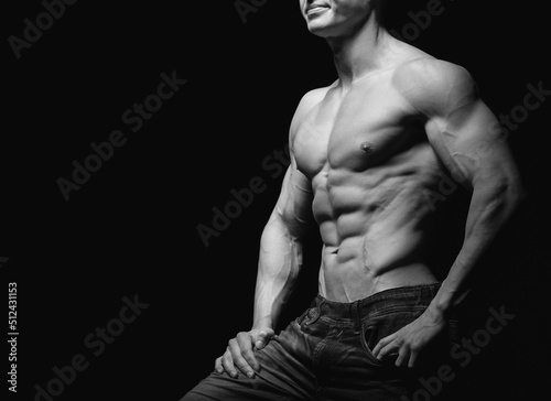 Fitness concept. Muscular and fit torso of young man having perfect abs, bicep and chest. Male hunk with athletic body on black background