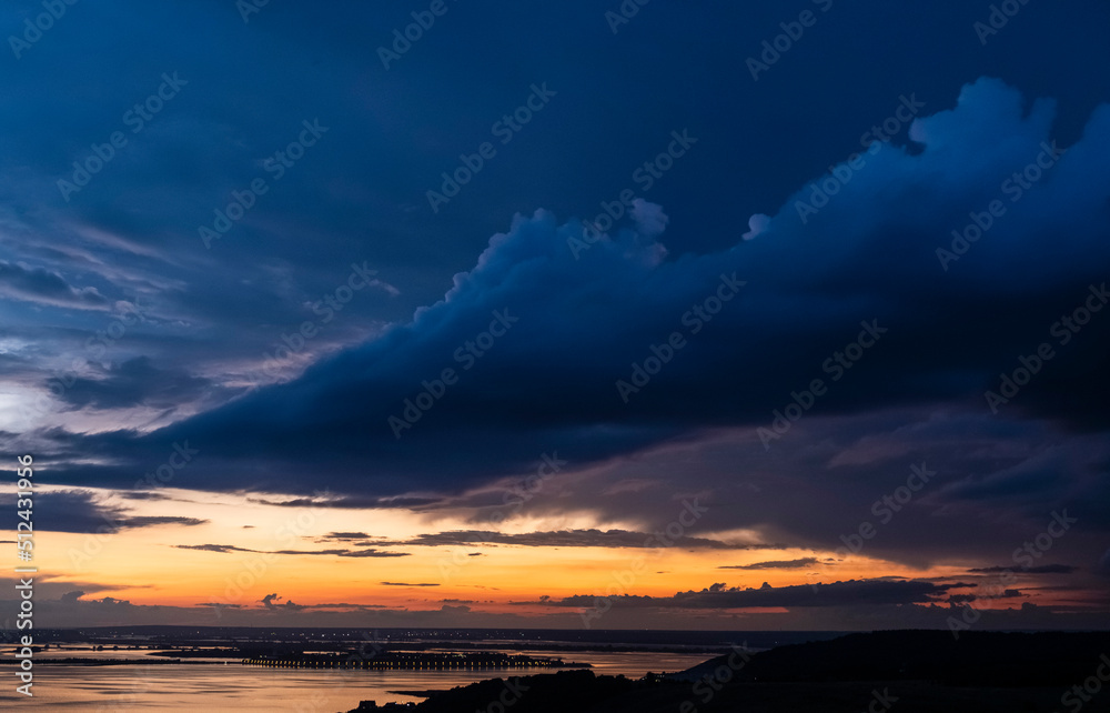 Dramatic sunset sky over Volga river, blue clouds hang over water