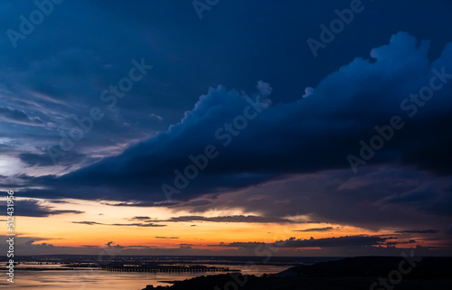Dramatic sunset sky over Volga river, blue clouds hang over water © Sergo