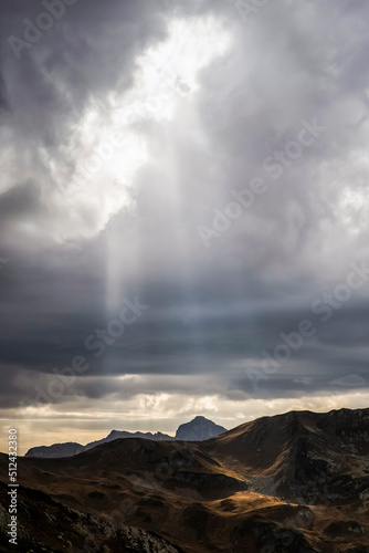 Sunbeams are seen through cloudy sky in Caucasus national park with a view on alpine landscape, peaks of rocky mountains and limestone geological formations. Caucasus nature reserve.