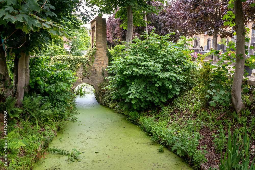 Petit pont de brique traversant un canal à coté d'un cimetière