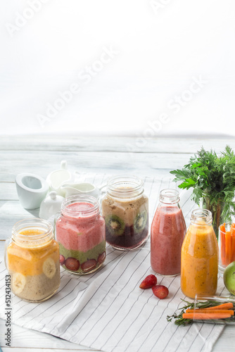 set of Three mason jars and two bottles with milkshakes or smoothie on white wooden background