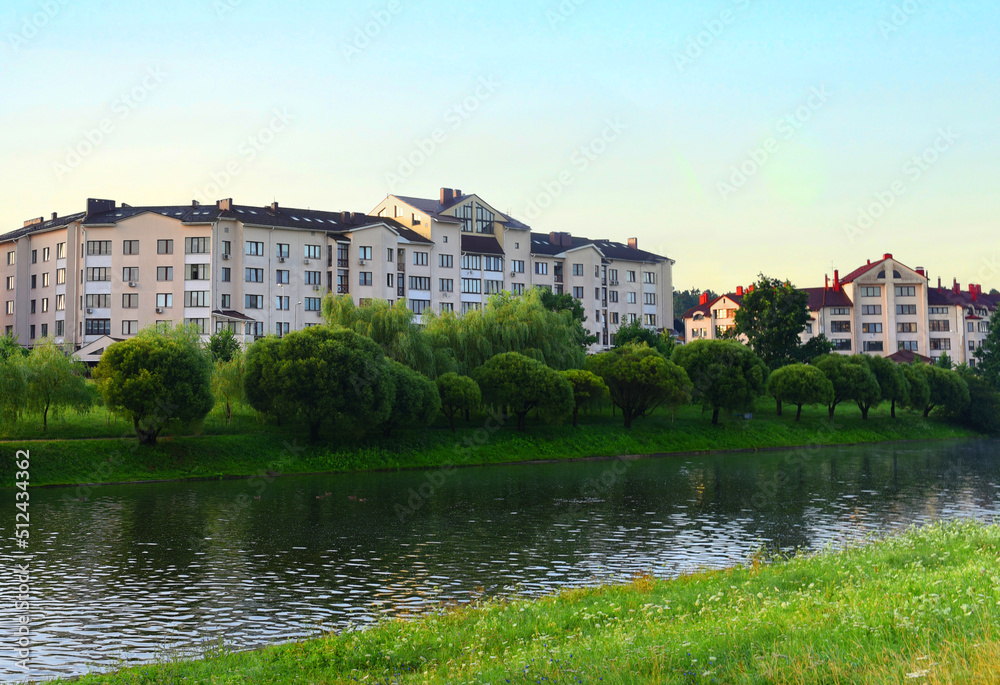 River on sunrise. Townhouses buildings and multi-floor home at waterfront. Morning on River in city. Suburb houses and residential building near river in Minsk. House in nature on shore on sunset..