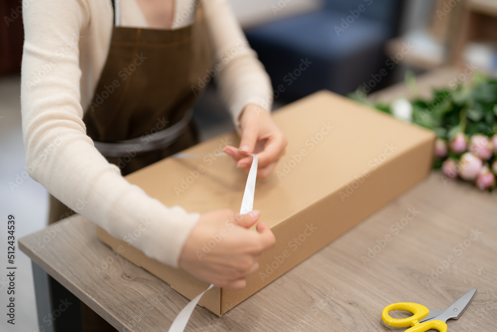 Woman Florist working in her workshop with flowers making a composition box on order Woman Florist working in her workshop with flowers making a composition box on order
