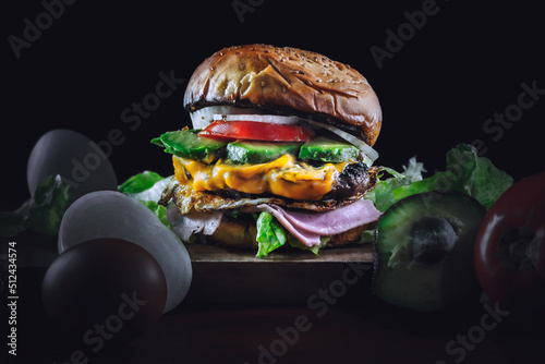 Deliciosa hamburguesa con vegetales, jamón, queso y huevo rodeada de ingrediente Fototapet