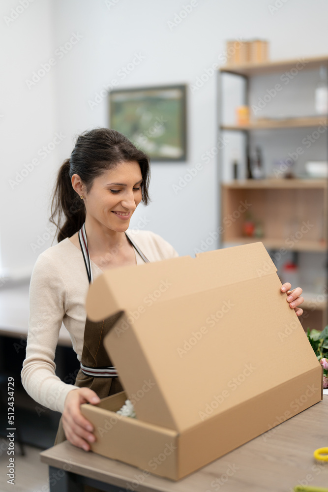 Smiling Woman Florist working in her workshop with flowers making a composition box on order Smiling Woman Florist working in her workshop with flowers making a composition box on order