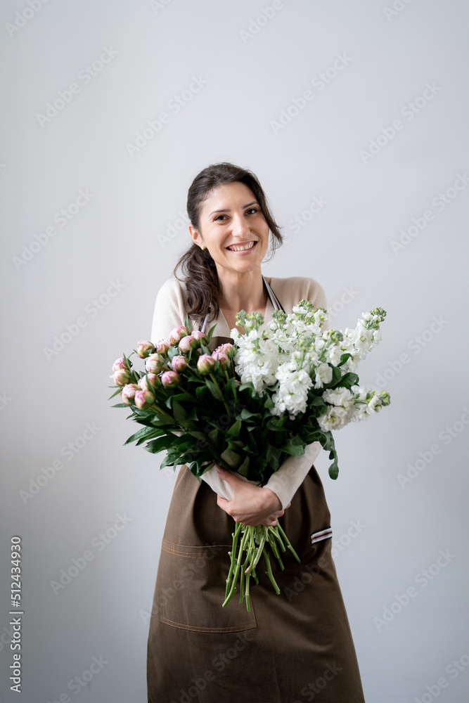 WOMAN florist EMBRACING a bunch of white and pink flowers on white background indoors WOMAN florist EMBRACING a bunch of white and pink flowers on white background indoors