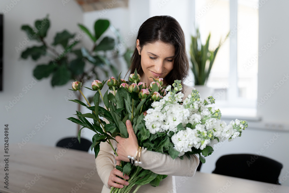Positive woman holding a huge bouquet of flowers in her office. Birthday present smile. Positive woman holding a huge bouquet of flowers in her office. Birthday present smile.