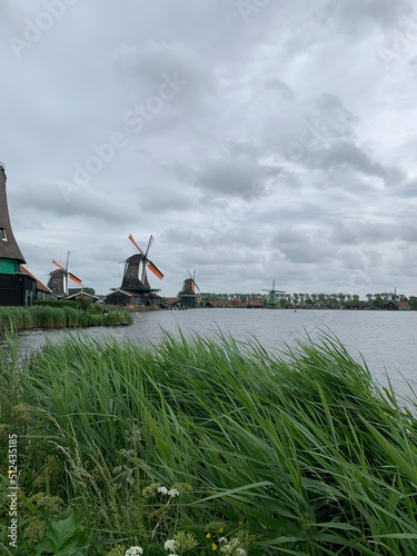 Historic wooden Dutch widmills with big blades next to the canal in small Zaanse Schans town near Amsterdam. It is a popular tourists attraction location. Zaanse Schans, North Holland, Netherlands photo