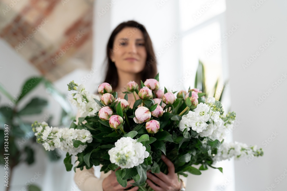 Positive woman holding a huge bouquet of flowers in her office. Birthday present smile. Positive woman holding a huge bouquet of flowers in her office. Birthday present smile.