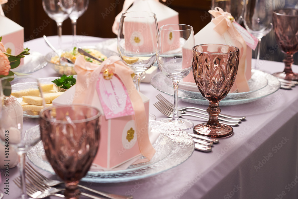 Gift boxes on a plate for guests on a served table for a holiday decorated with rose flowers Gift boxes on a plate for guests on a served table for a holiday decorated with rose flowers