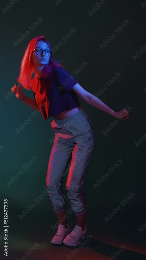 Neon dance. Cyberpunk party. Hip hop freestyle. Confident cool teenager girl enjoying nightlife in vivid glowing light on dark background vertical. Neon dance. Cyberpunk party. Hip hop freestyle. Confident cool teenager girl enjoying nightlife in vivid glowing light on dark background vertical.