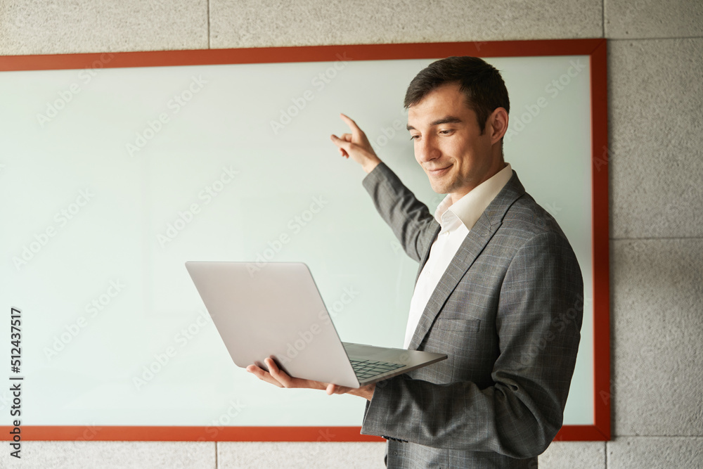 Male teaching a lesson online while pointing at whiteboard Male teaching a lesson online while pointing at whiteboard