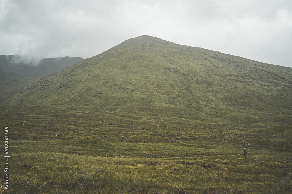 Lone hiker under large mountain