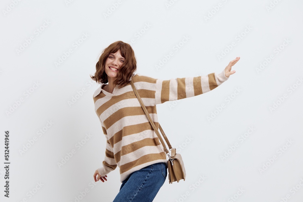 a lovely woman is standing on a white background in a striped sweater spinning in different directions with her arms spread out in different directions smiling cheerfully a lovely woman is standing on a white background in a striped sweater spinning in different directions with her arms spread out in different directions smiling cheerfully
