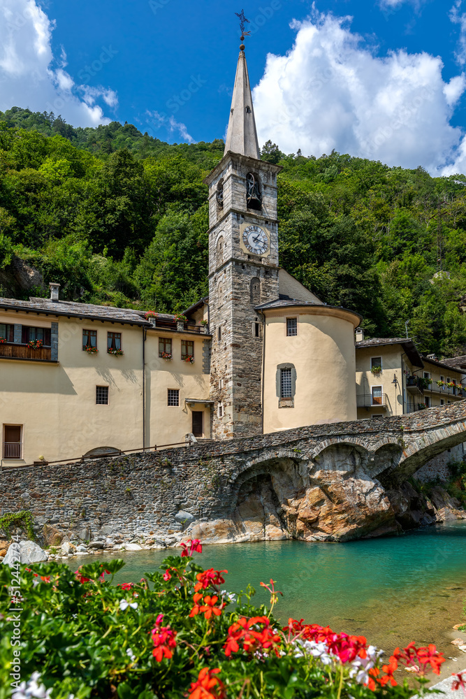 Old church with the spire and mountain river in town of Fontainemore, Italy.