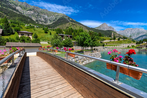 Wooden bridge over small lake and mountains on background in Northern Italy.