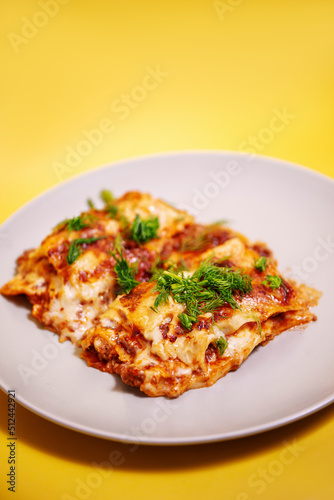 Lasagne on a white plate on a yellow background