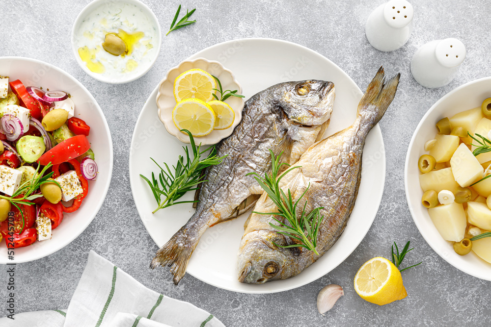 Dorada fish sea bream baked, fresh vegetable greek salad, boiled potatoes with garlic and olives and tzatziki dip. Healthy food. Mediterranean diet. Dorada fish sea bream baked, fresh vegetable greek salad, boiled potatoes with garlic and olives and tzatziki dip. Healthy food. Mediterranean diet.