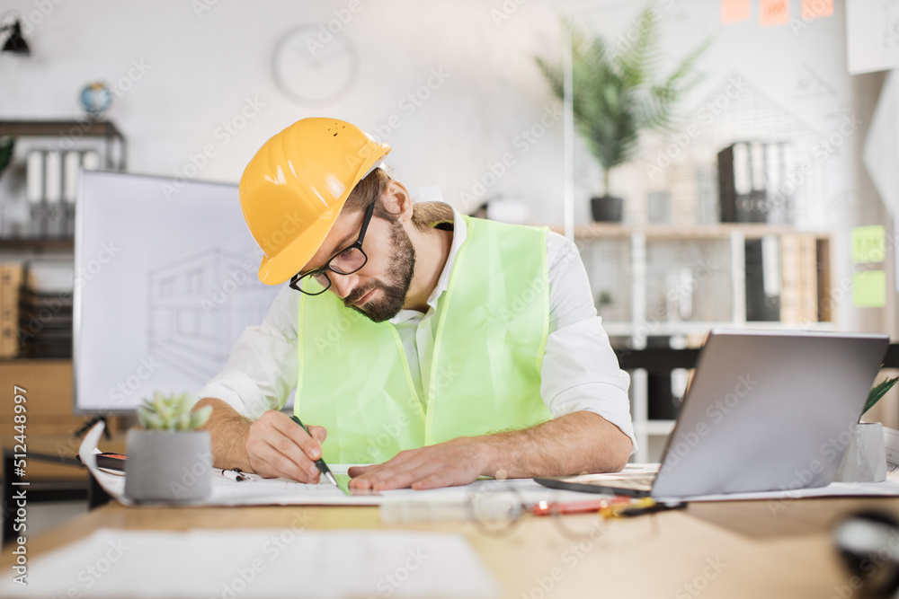 Architect man or male builder hold pen and ruler, writing and drawing architectural project, work on laptop computer on the desk at workplace. Architect man or male builder hold pen and ruler, writing and drawing architectural project, work on laptop computer on the desk at workplace.