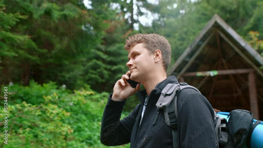 A portrait of a guy with a backpack stands in the forest and talks on the phone. A portrait of a guy with a backpack stands in the forest and talks on the phone.