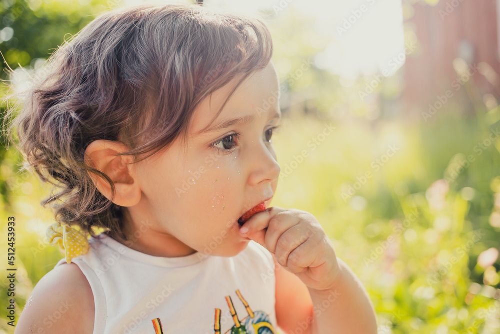 little girl eating strawberry in garden little girl eating strawberry in garden
