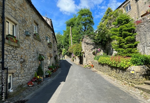 View up  Castle Hill  with old stone cottages  trees  and plants  on a sunny day in  Settle  UK