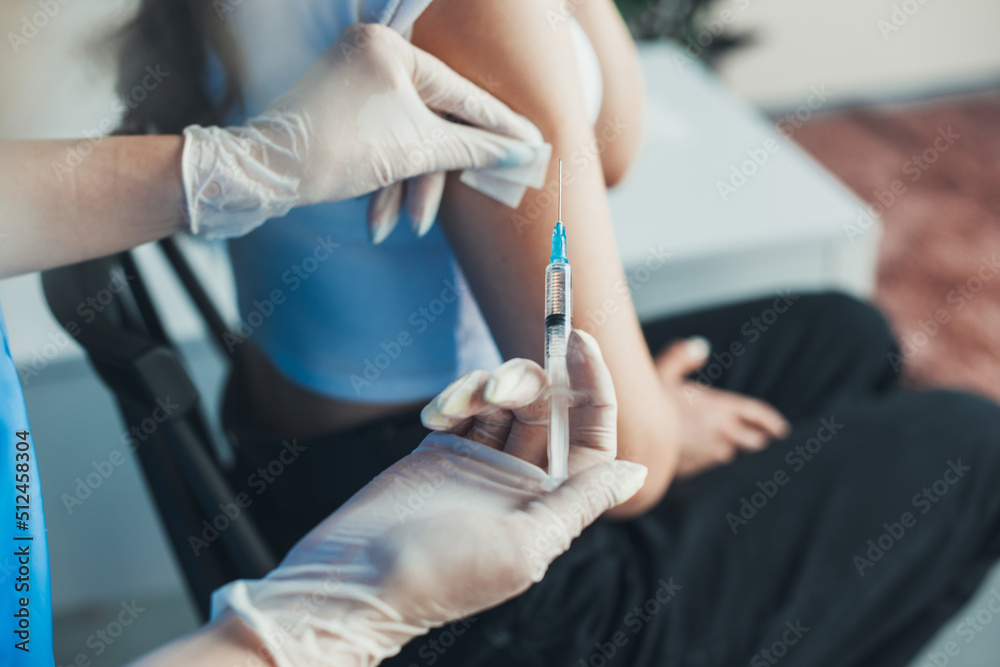 Medical assistant's hand disinfecting patient's arm preparing to give an intramuscular injection of a Covid-19 vaccine. Pandemic prevention. Coronavirus - obrazy, fototapety, plakaty 