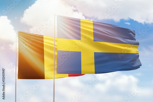 Sunny blue sky and flags of sweden and belgium