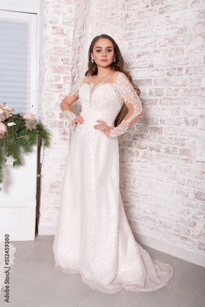 Bride in a white dress against a brick wall.