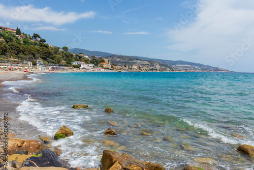 Waves against rock and, in the background, the italian coast with the town of Arma di Taggia. Italian Riviera in the province of Imperia, Liguria, Italy photo