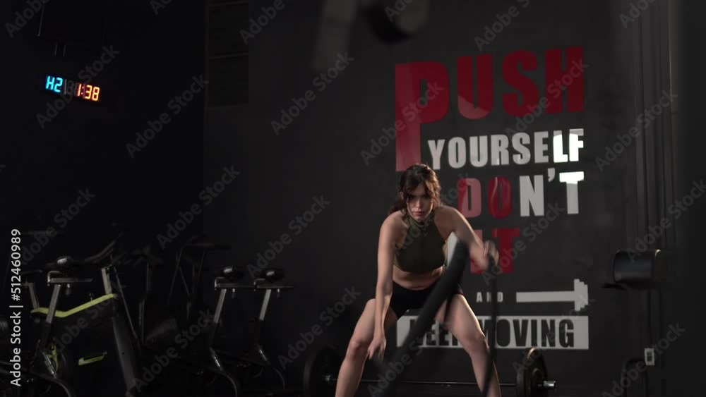 Young woman slim body training and working out with battle rope at fitness gym Young woman slim body training and working out with battle rope at fitness gym