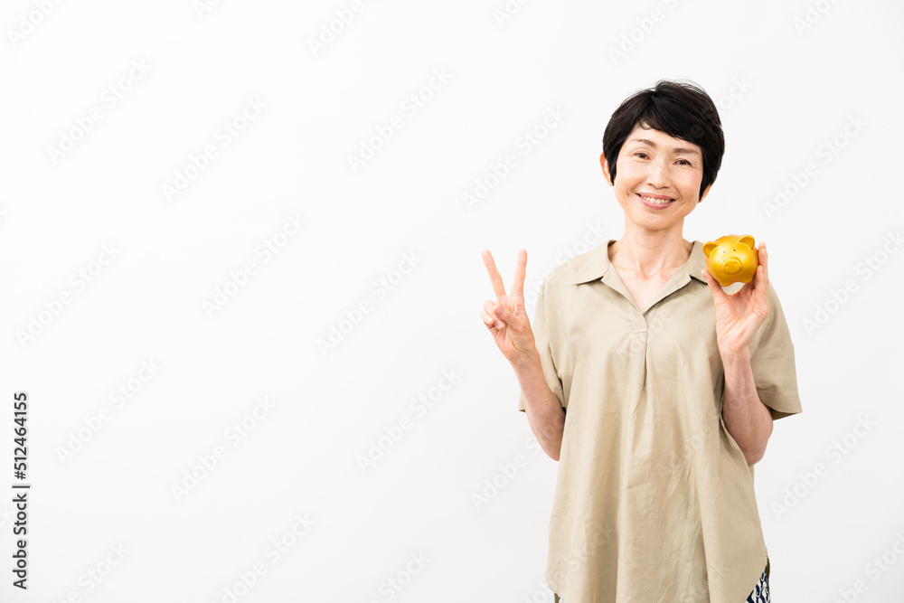 ブタの貯金箱を持ってピースサインをするミドル女性 ブタの貯金箱を持ってピースサインをするミドル女性