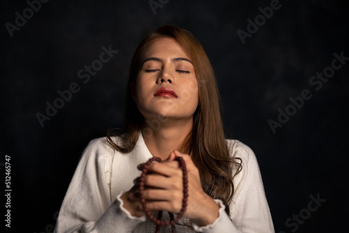 Woman sitting and praying for blessings from god in a room with black background