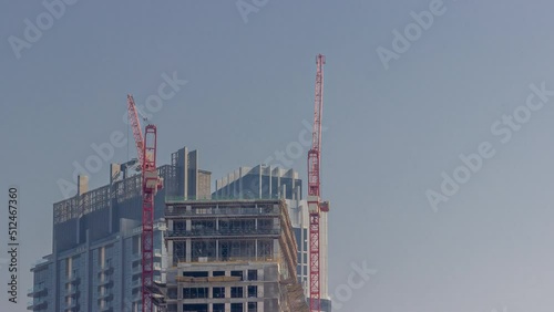 Two cranes working on constraction site of new skyscraper timelapse. High rise tower and building activity at the evening photo