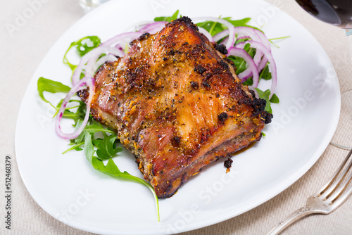 Image of tasty pork ribs baked under sauce, served with arugula and onion salad