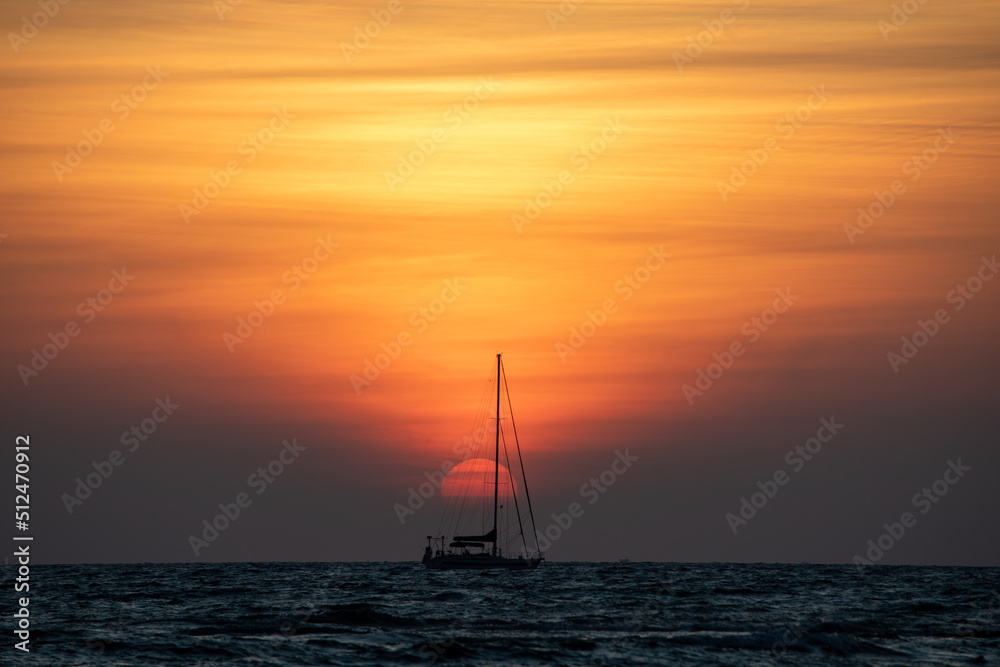 A sailing boat moored under a beautiful tropical sunset 
